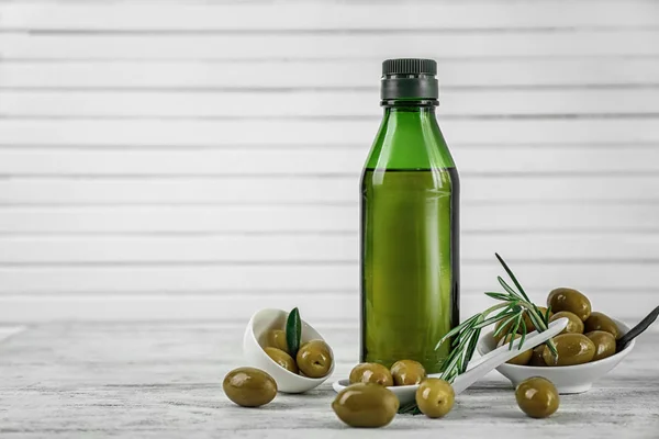 Olives and oil on wooden background — Stock Photo, Image