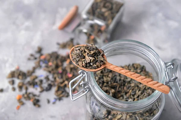 Jar and spoon with dry tea on table — Stock Photo, Image