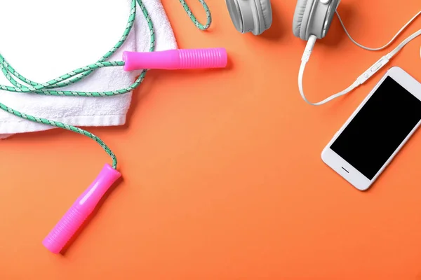 Flat lay composition with jumping rope, smartphone and towel on color background. Gym workout — Stock Photo, Image