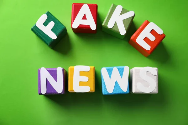 Text falska nyheter gjorda av kuber med bokstäver på färg bakgrunden — Stockfoto