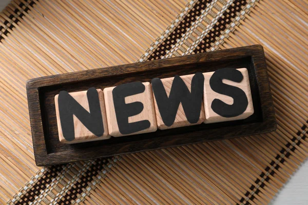 Word NEWS made of cubes with letters on bamboo mat — Stock Photo, Image