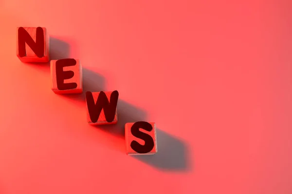 Word News aus Würfeln mit Buchstaben auf farbigem Hintergrund — Stockfoto