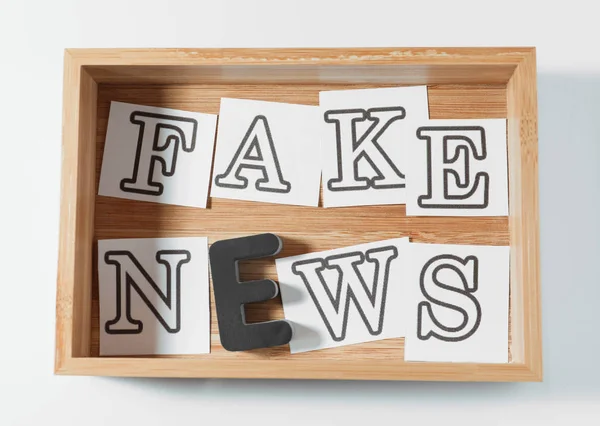 Text falska nyheter gjorda av bokstäver i trälåda på vit bakgrund — Stockfoto