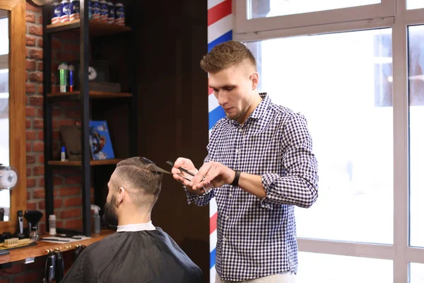 Professionel barber arbejder med klient i frisørsalon - Stock-foto