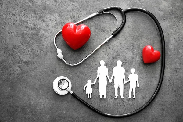 Figura di famiglia, cuori rossi e stetoscopio su sfondo grigio. Concetto sanitario — Foto Stock
