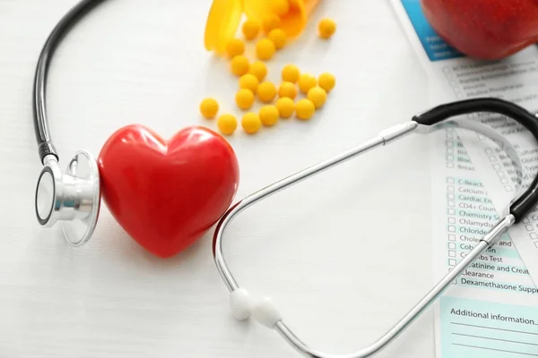 Estetoscopio con corazón rojo y pastillas sobre fondo blanco. Concepto de salud —  Fotos de Stock