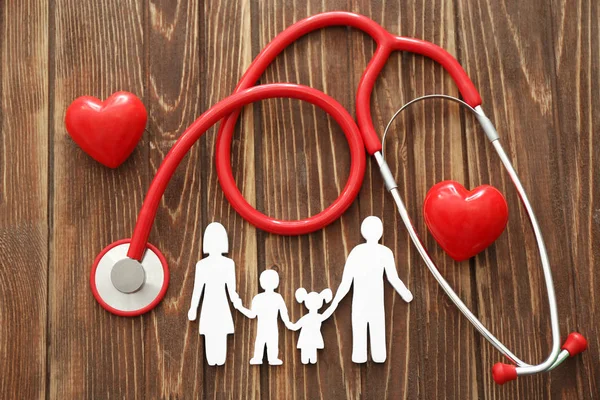 Figura di famiglia, cuori rossi e stetoscopio su sfondo di legno. Concetto sanitario — Foto Stock