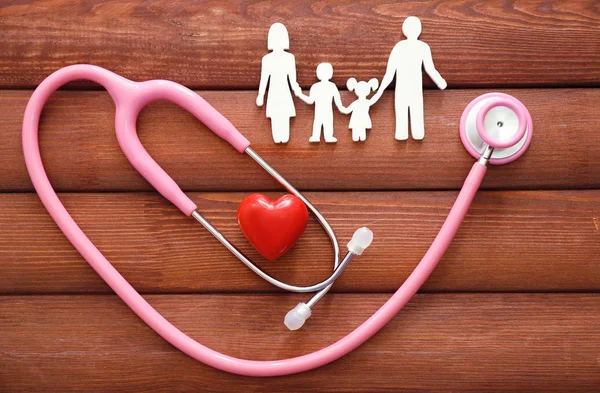 Figura di famiglia, cuore rosso e stetoscopio su sfondo di legno. Concetto sanitario — Foto Stock