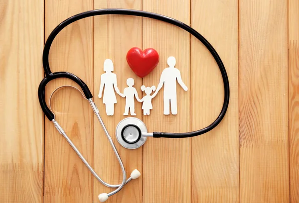 Figura di famiglia, cuore rosso e stetoscopio su sfondo di legno. Concetto sanitario — Foto Stock