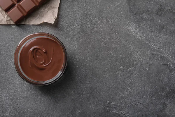 Schüssel mit schmackhafter geschmolzener Schokolade auf grauem Tisch, Draufsicht — Stockfoto