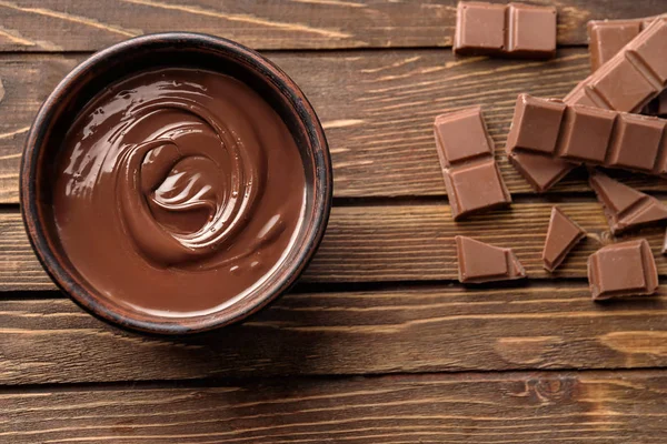 Tasty melted and solid chocolate on wooden background, top view — Stock Photo, Image