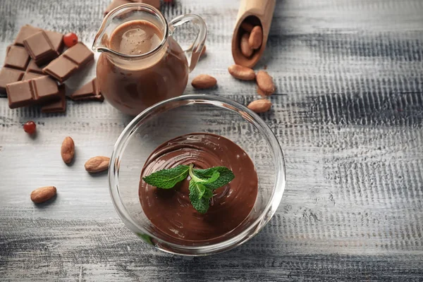 Cuenco de vidrio con sabroso chocolate derretido en mesa de madera —  Fotos de Stock