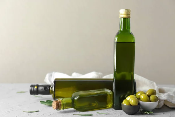 Bottles with olive oil on table against light background — Stock Photo, Image