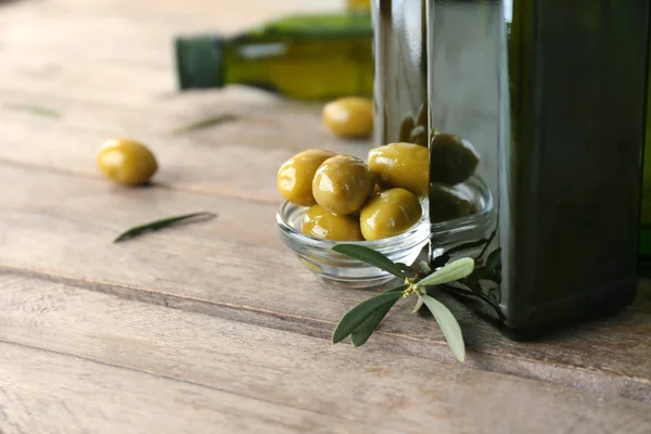 Fresh olives and bottle with oil on wooden background, closeup — Stock Photo, Image