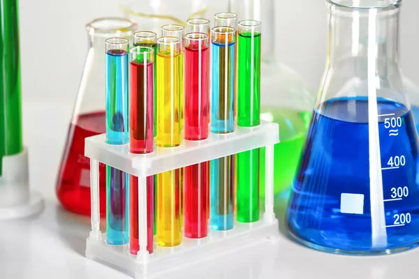 Tubes à essai et fiole avec liquides colorés sur la table — Photo