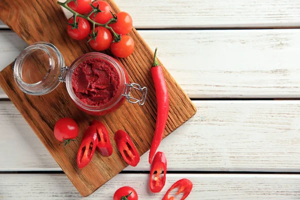 Brett mit roter Sauce, Kirschtomaten und Chilischoten auf Holzgrund, Draufsicht — Stockfoto