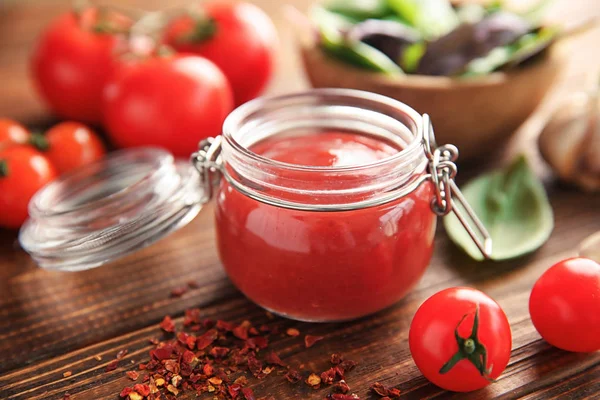 Köstliche rote Sauce im Glas und Zutaten auf dem Tisch — Stockfoto