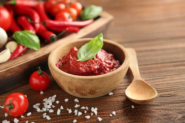 Deliziosa salsa rossa in ciotola e ingredienti in tavola — Foto Stock