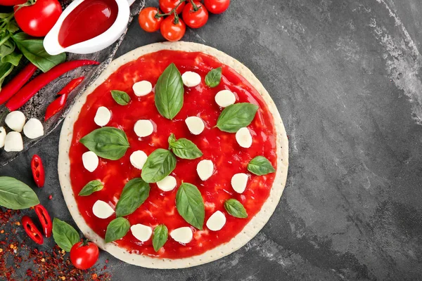 Raw dough for pizza with red sauce and ingredients on table, top view — Stock Photo, Image