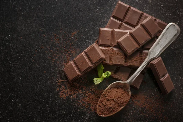 勺子与可可粉和美味的巧克力在黑暗的背景下, 顶部视图 — 图库照片