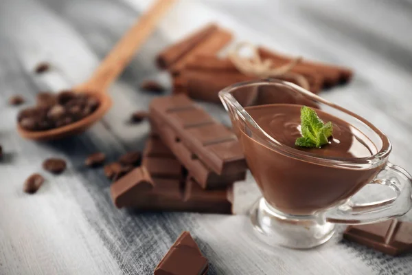 Σαλτσιέρα με νόστιμα λειωμένα σοκολάτα στο ξύλινο τραπέζι — Φωτογραφία Αρχείου
