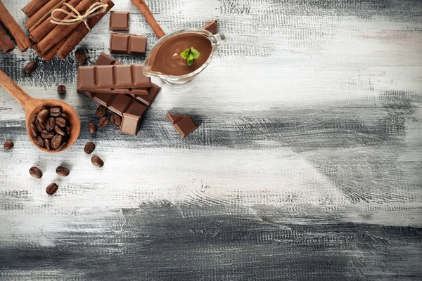 Flat lay composition with tasty chocolate, cinnamon sticks and coffee beans on wooden background — Stock Photo, Image