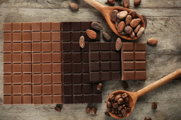 Leckere Schokolade, Kakao und Kaffeebohnen auf Holztisch, Draufsicht — Stockfoto
