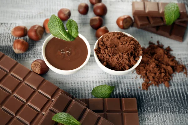 Composition with tasty chocolate and cocoa powder on wooden table — Stock Photo, Image