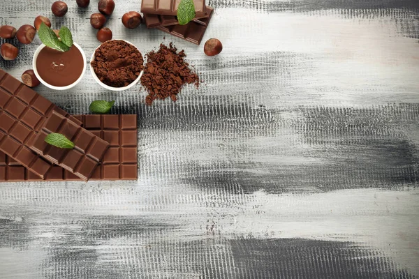 Komposition mit schmackhafter Schokolade und Kakaopulver auf Holztisch, Draufsicht — Stockfoto