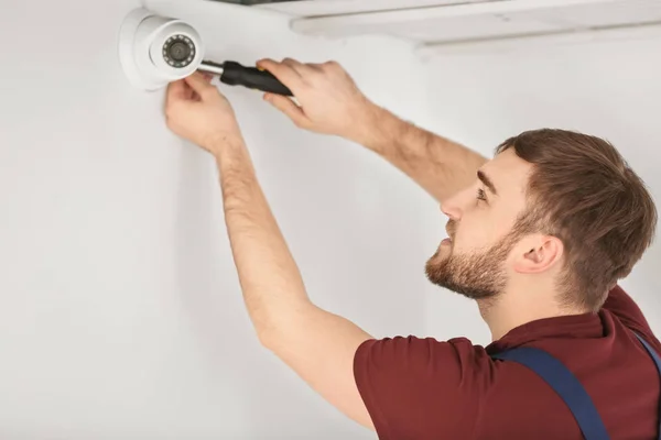 Electrician installing security camera indoors — Stock Photo, Image