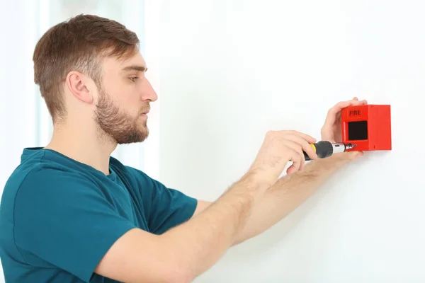 Electricista joven instalando unidad de alarma de incendios en la pared — Foto de Stock