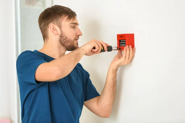 Electricista joven instalando unidad de alarma de incendios en la pared — Foto de Stock