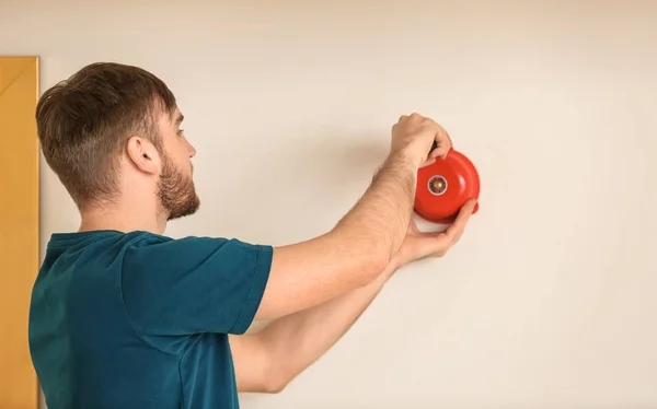 Young man installing alarm bell on wall — Stock Photo, Image