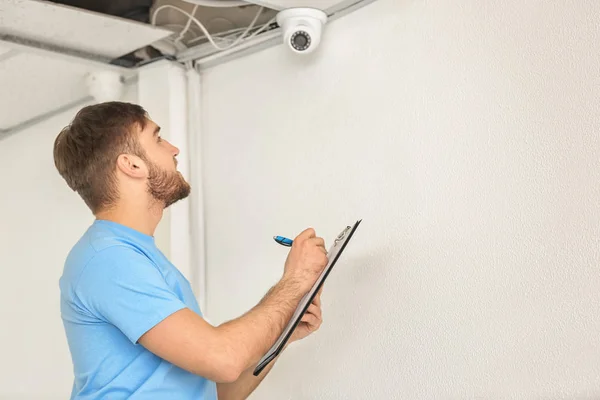 Electrician installing security camera indoors — Stock Photo, Image