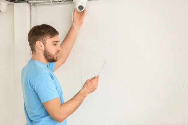 Electrician installing security camera indoors — Stock Photo, Image