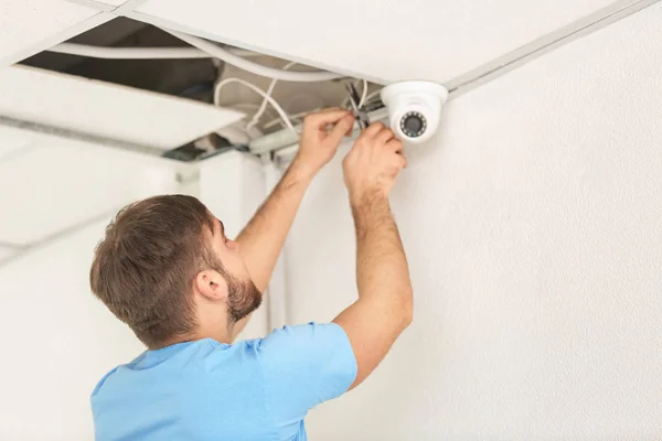 Electrician installing security camera indoors — Stock Photo, Image