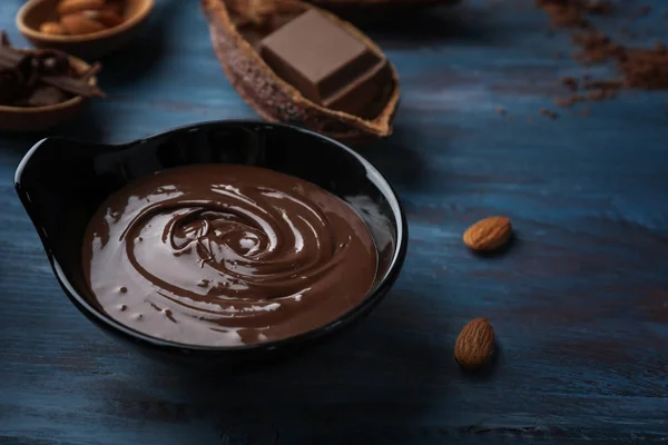 Schüssel mit geschmolzener Schokolade auf Holztisch — Stockfoto