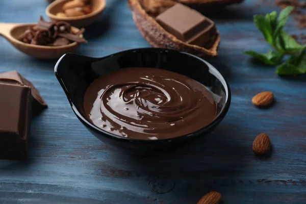 Bowl with molten chocolate on wooden table — Stock Photo, Image