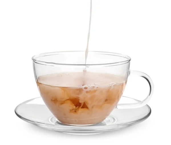 Mleko spływał do szklanki z aromatycznej herbaty na białym tle — Zdjęcie stockowe