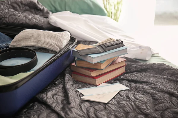 Гаманець, документи і відкрита валіза з упакованими речами на ліжку — стокове фото