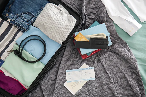 钱包, 文件和打开行李箱与包装的东西在床上, 顶部视图 — 图库照片