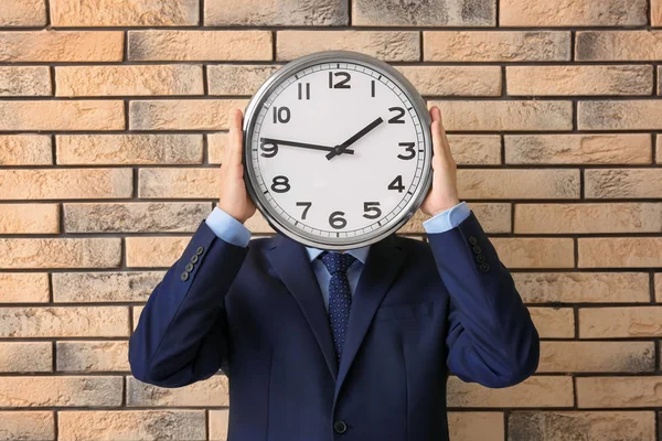 Un uomo che tiene l'orologio su sfondo mattone. Concetto di gestione temporale — Foto Stock