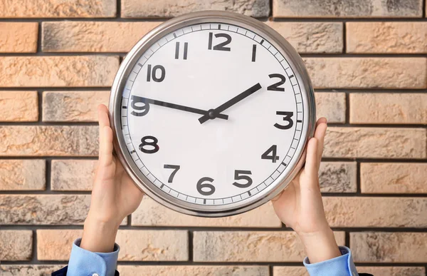 Man holding clock on brick background. Time management concept — Stock Photo, Image