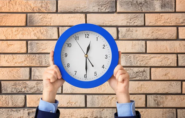 Man håller klockan på tegel bakgrund. Time management koncept — Stockfoto