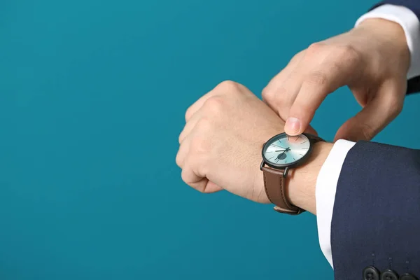 Чоловік дивиться на свій годинник на кольоровому фоні, крупним планом. Концепція управління часом — стокове фото