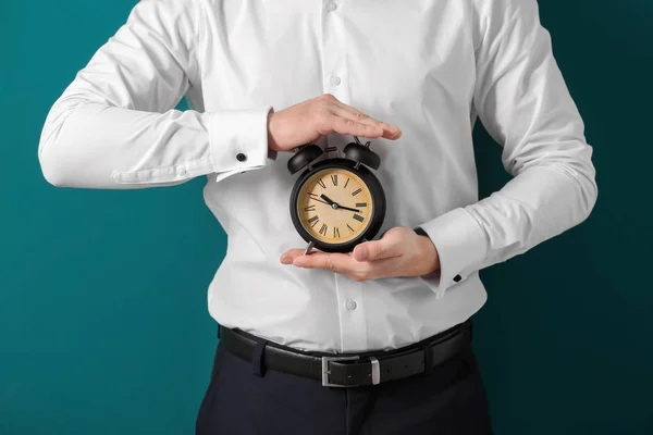 Hombre con despertador en el fondo de color. Concepto de gestión del tiempo — Foto de Stock