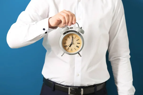 Hombre con despertador en el fondo de color. Concepto de gestión del tiempo — Foto de Stock