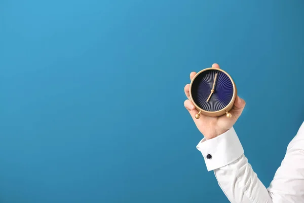 Hombre sosteniendo el reloj en el fondo de color. Concepto de gestión del tiempo — Foto de Stock