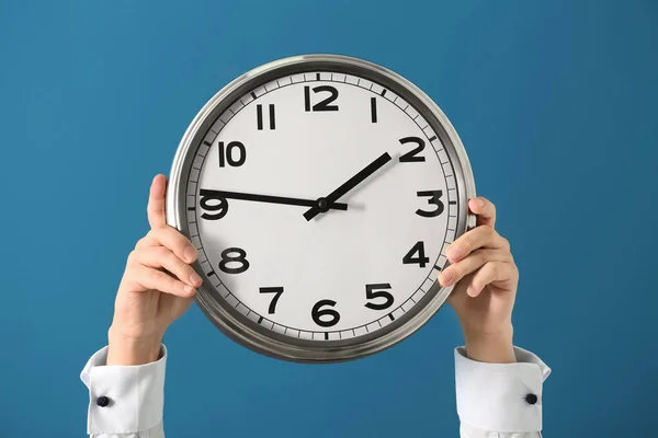 Man holding clock on color background. Time management concept