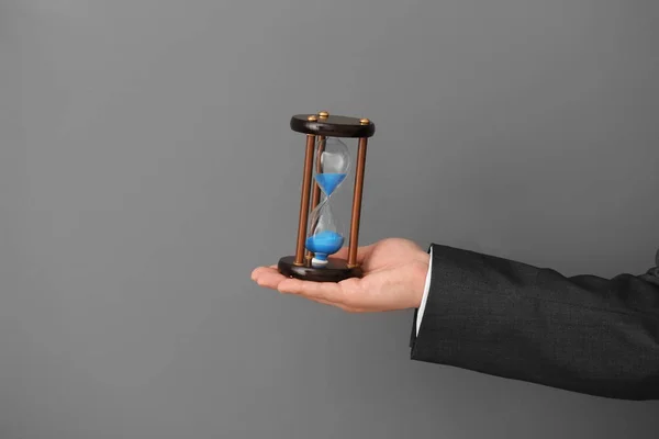Man holding hourglass on gray background. Time management concept — Stock Photo, Image